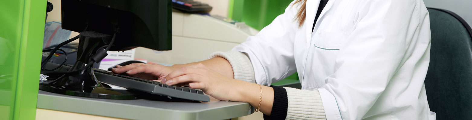 A person typing on a keyboard with a green wall in the background.