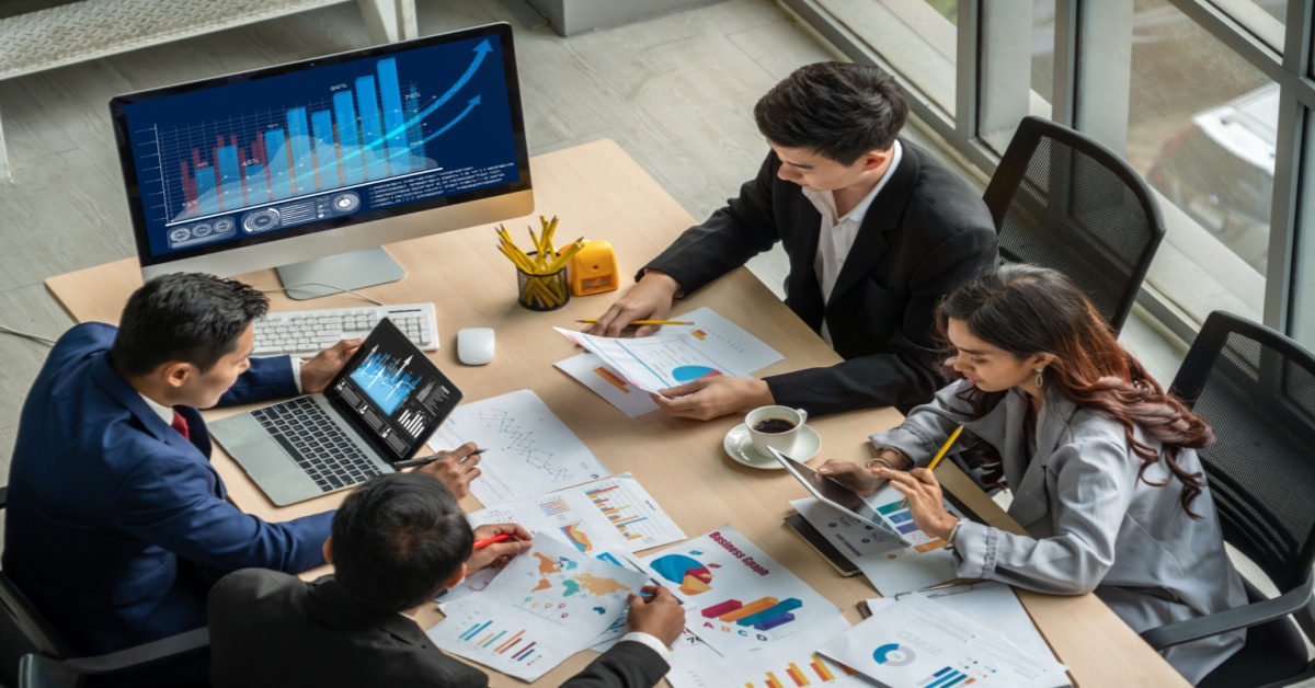 Businesspeople reviewing analytics at a desk in the office. Dynamics 365 for Financial Services